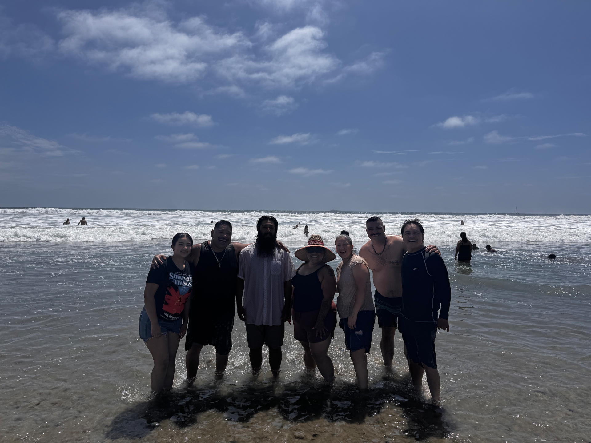 Church family standing together in the ocean after a beach baptism