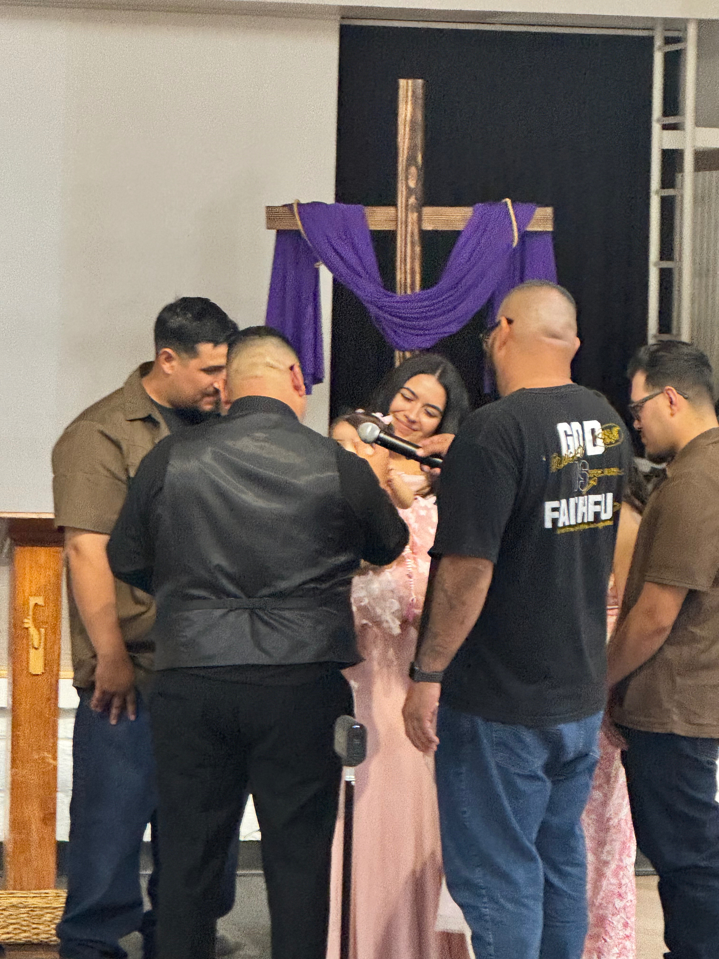 Leaders gathered around a young woman praying at the altar beneath the cross