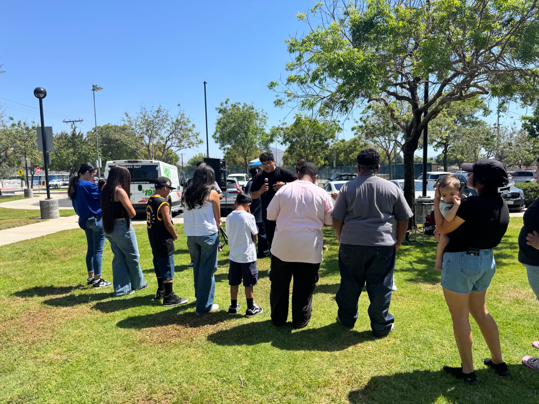 Church family bowed in prayer as the Word is preached in the park