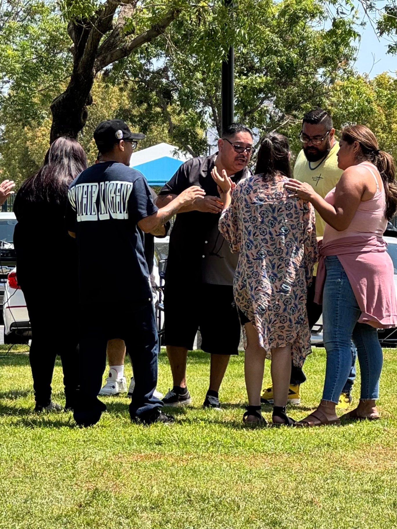 A prayer circle laying hands on one another during outreach